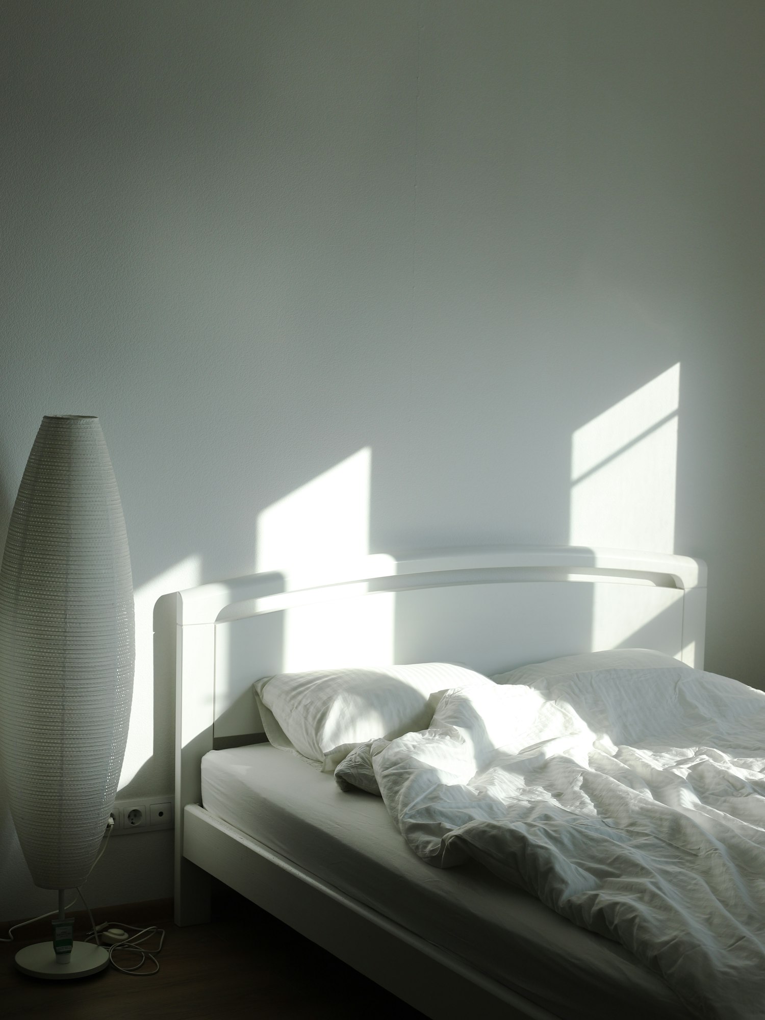 Bett und Stehleuchte im Morgenlicht